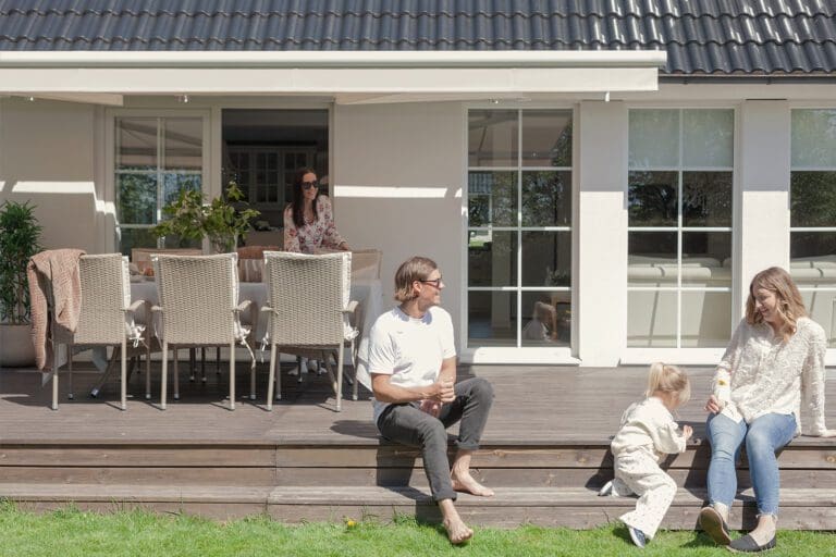 Familj under Astro terrassmarkis på uteplats med effektivt solskydd och hög komfort.
