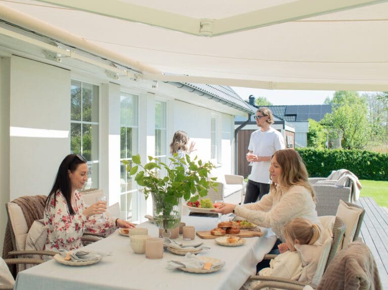 Familj under Astro terrassmarkis på uteplats med effektivt solskydd och hög komfort.